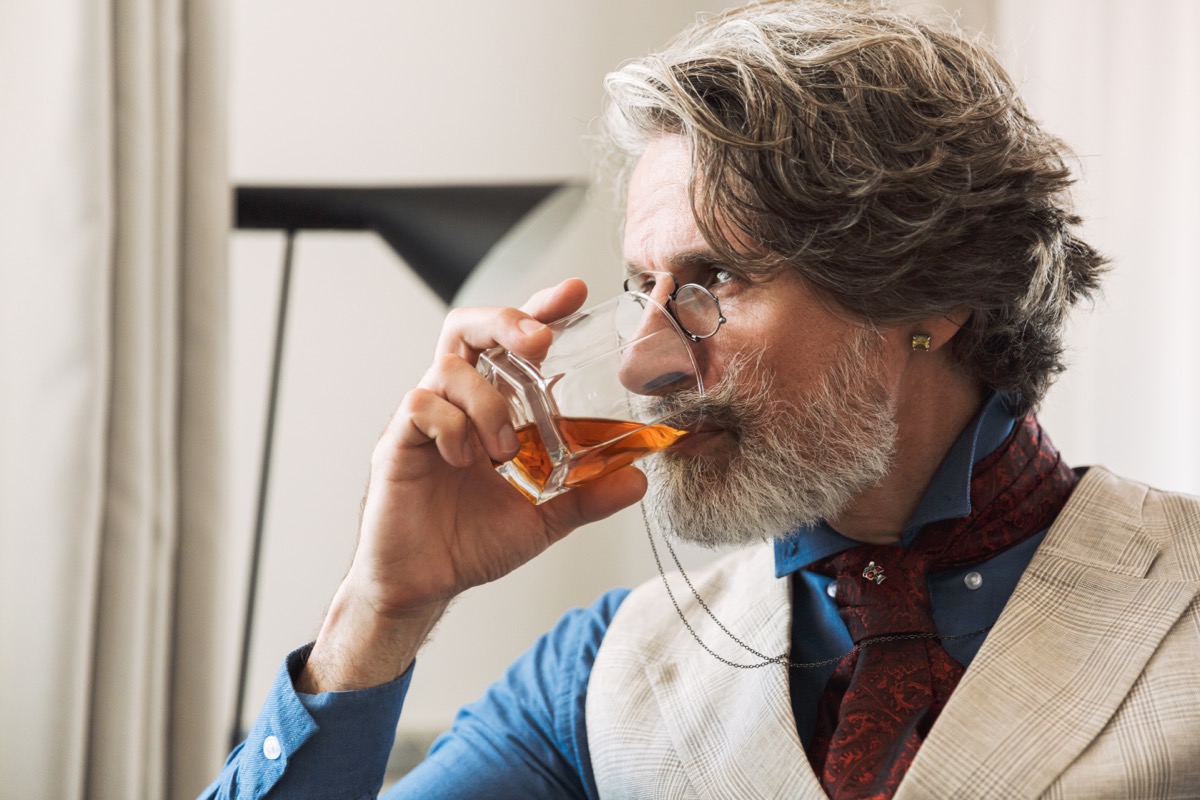 mature man drinking whiskey in clear glass