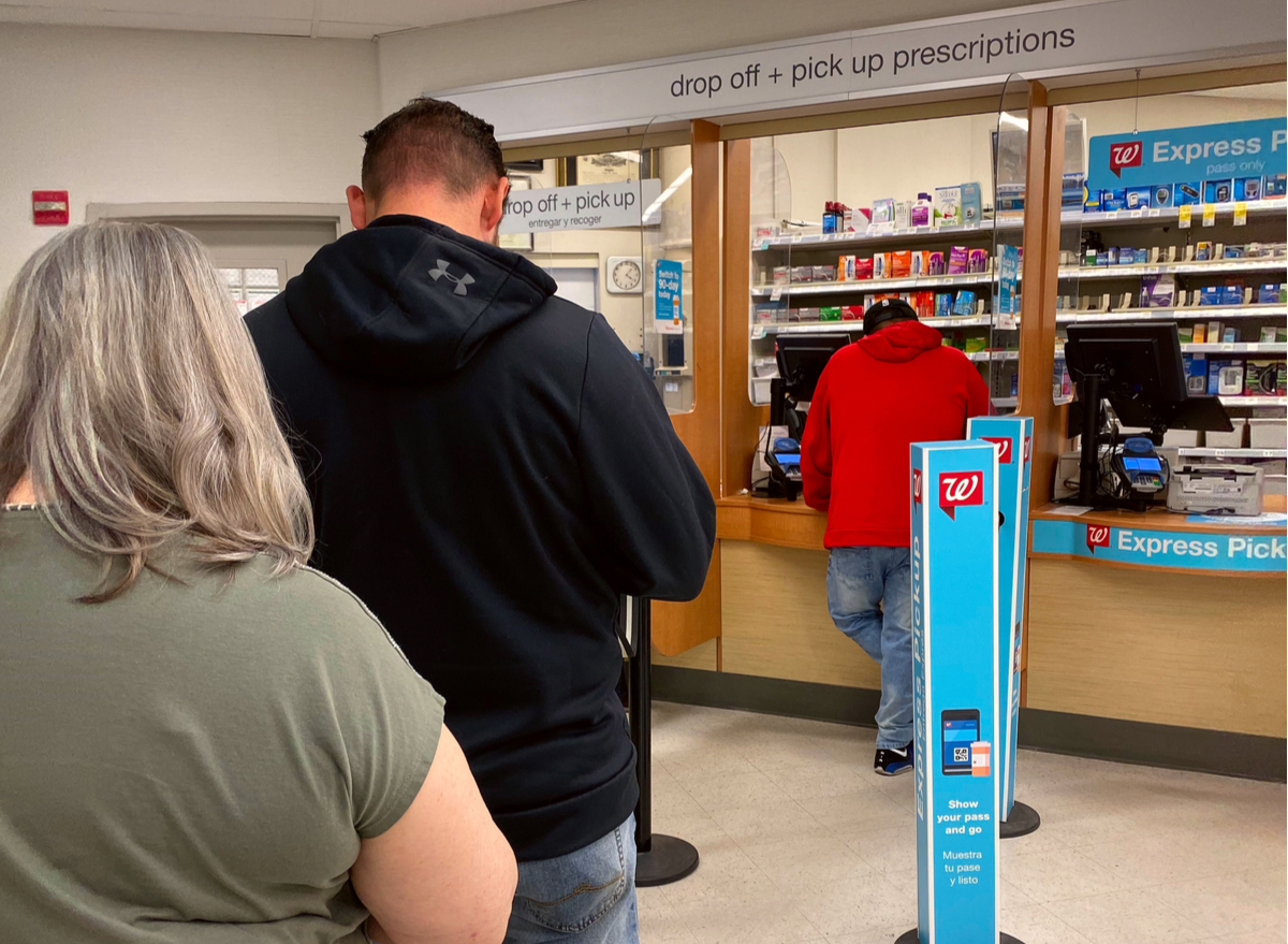People standing in line at a drug store counter.