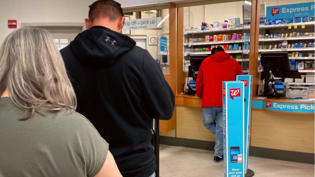 People standing in line at a drug store counter.
