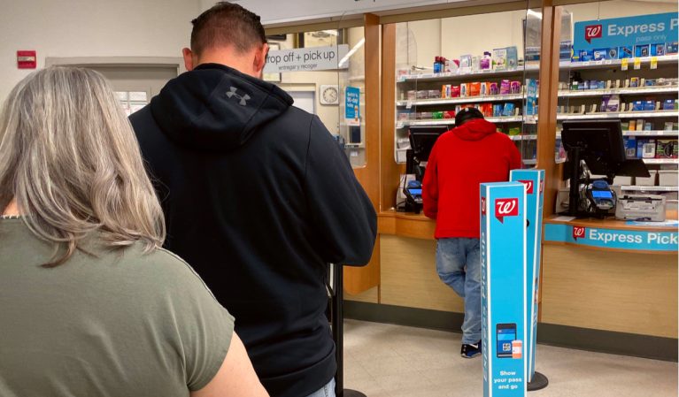 People standing in line at a drug store counter.