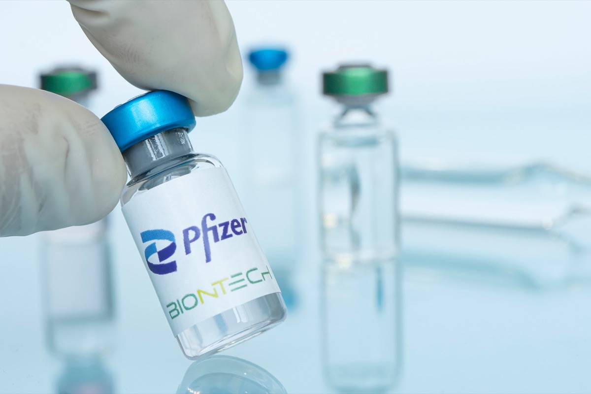 Glass bottle with logo Pfizer and BioNTech in the doctor's hand.