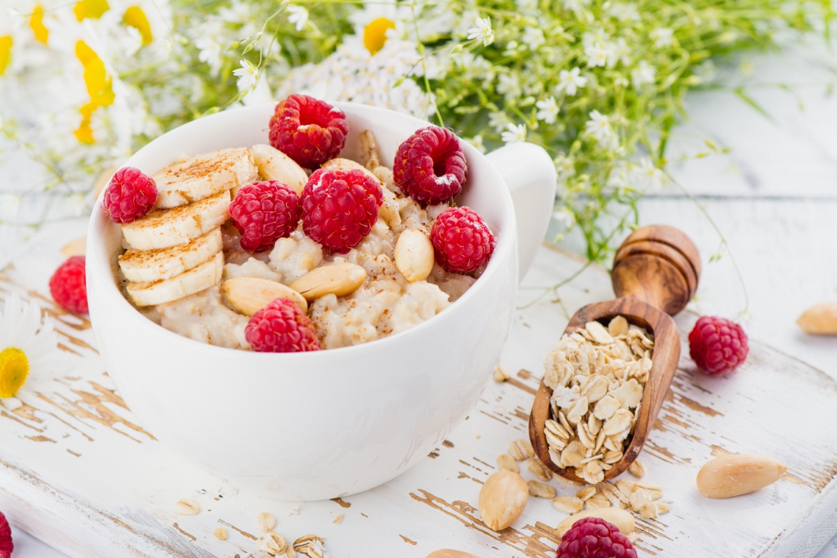 oatmeal topped with raspberries and bananas in a white bowl