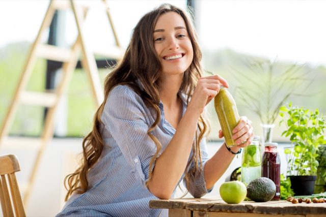 young woman holding bottle of green juice