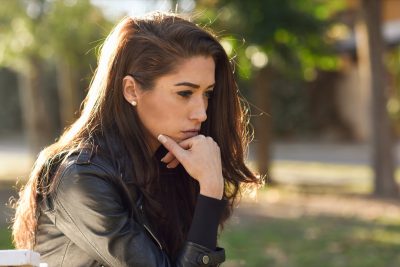 young woman looking stressed and sitting outdoors