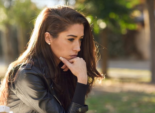 young woman looking stressed and sitting outdoors