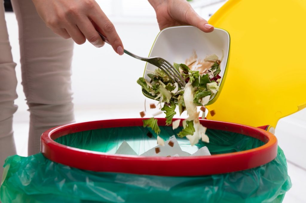 throwing salad away in trash can