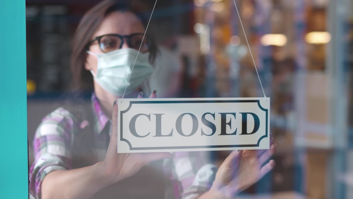woman putting closed sign into restaurant window