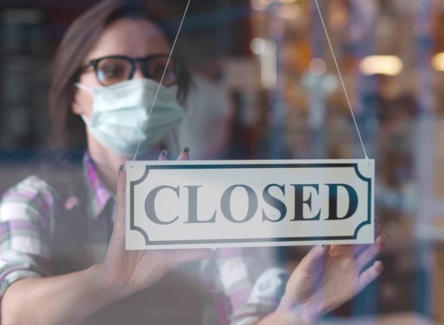 woman putting closed sign into restaurant window