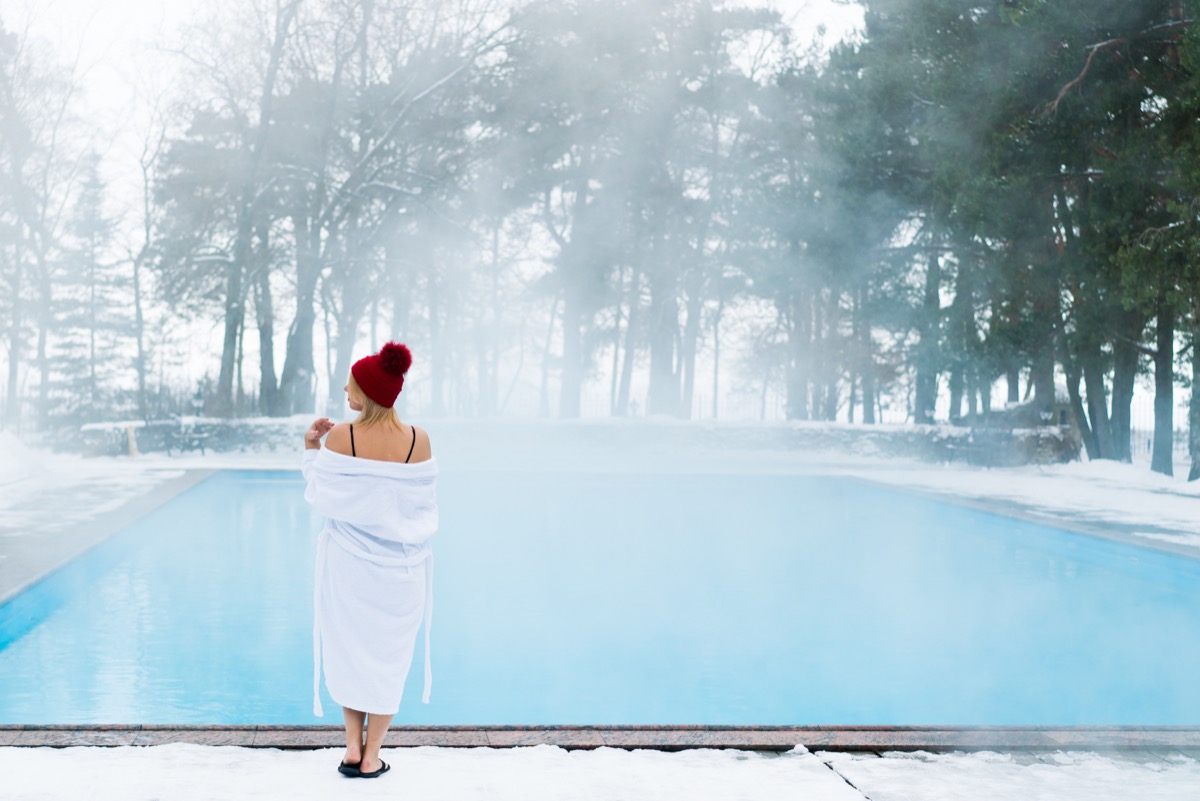 woman in robe getting into pool on cold day in winter