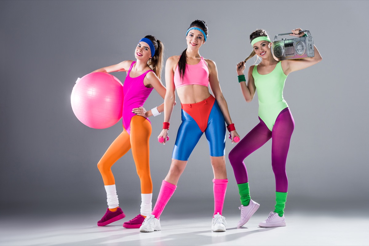 Sporty women with sports equipment and tape recorder smiling at camera.