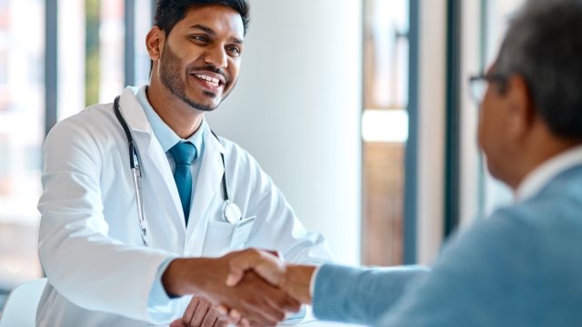 Male doctor and his patient shaking hands in the hospital.