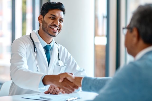 Male doctor and his patient shaking hands in the hospital.