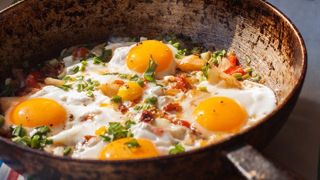 Fried eggs in a skillet with eggs and garnish