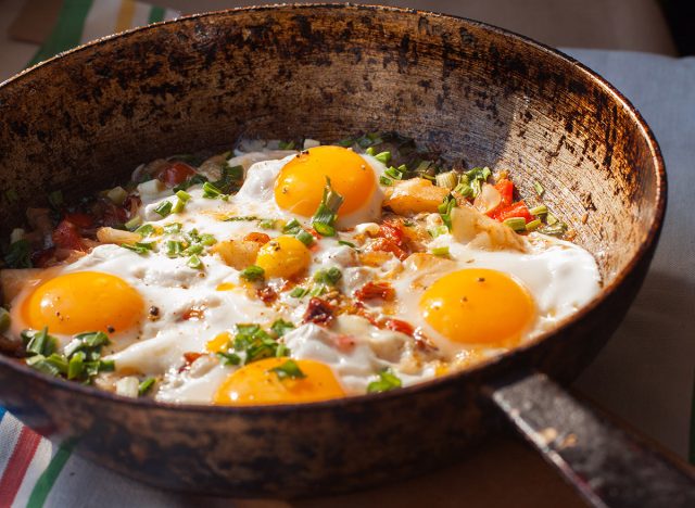 Fried eggs in a skillet with eggs and garnish