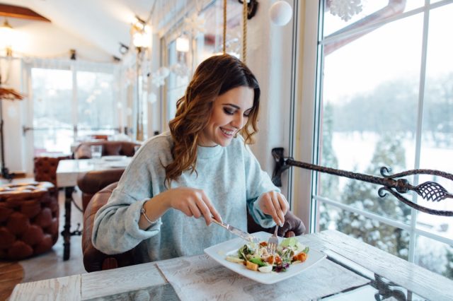 happy woman eating salad at a restaurant