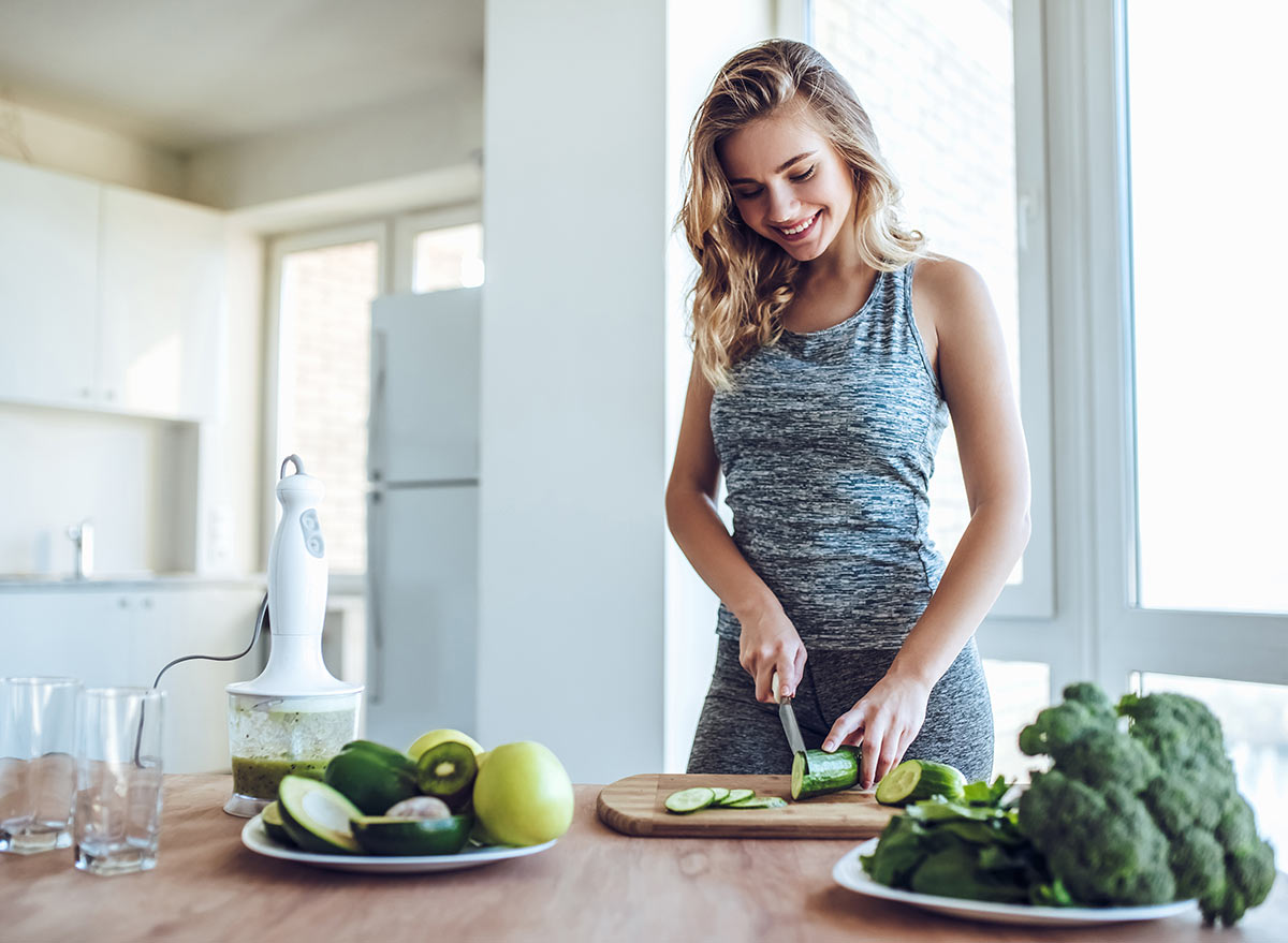 Healthy happy woman making green juice