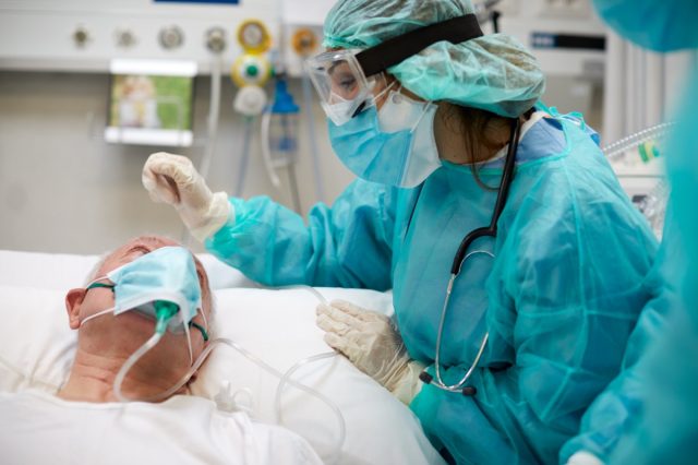 The nurse comforts the patient with covid in the intensive care unit
