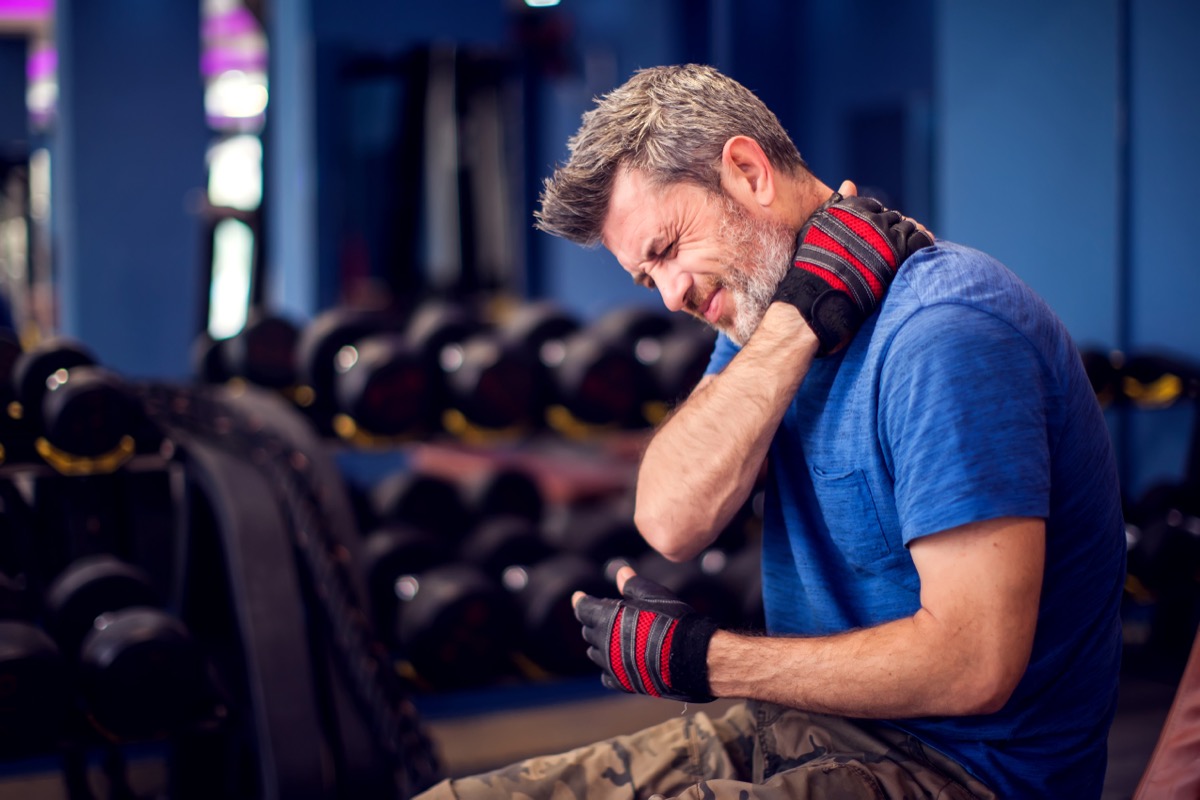 middle aged man in gym experiencing neck or shoulder pain
