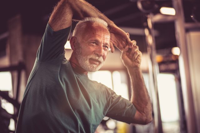 older man stretching in gym