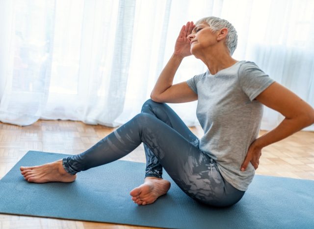 older woman on yoga mat with back pain