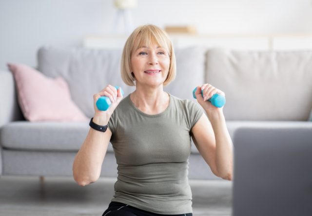older woman doing dumbbell workouts at home