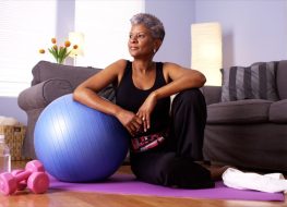 woman with gray hair workout out with yoga ball at home