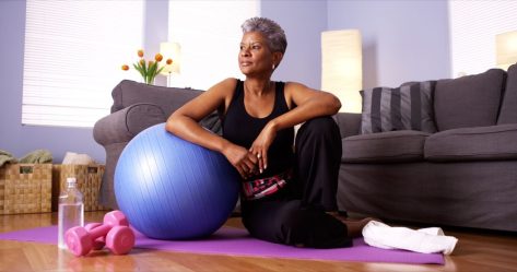 woman with gray hair workout out with yoga ball at home