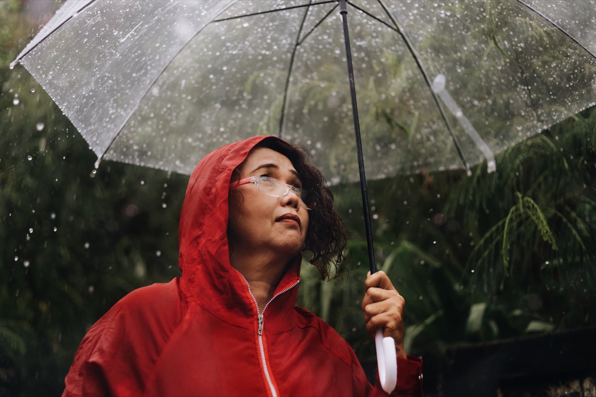 older woman outdoors on rainy day holding umbrella