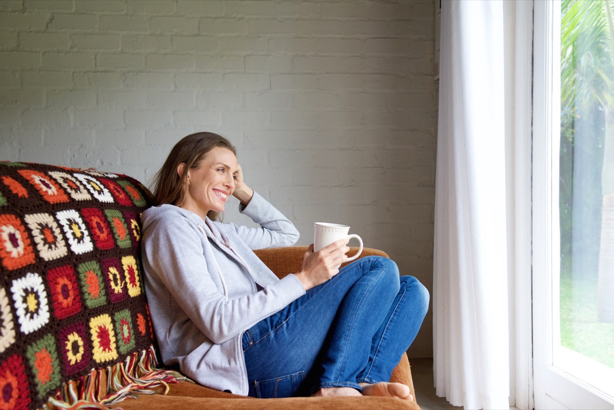 middle-aged woman sitting on couch in jeans smiling