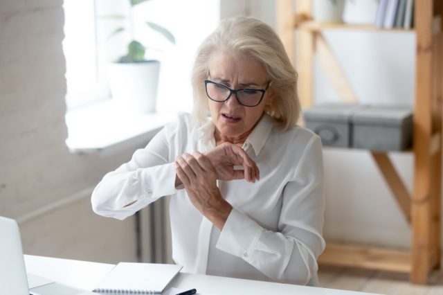 older woman sitting at desk with wrist pain