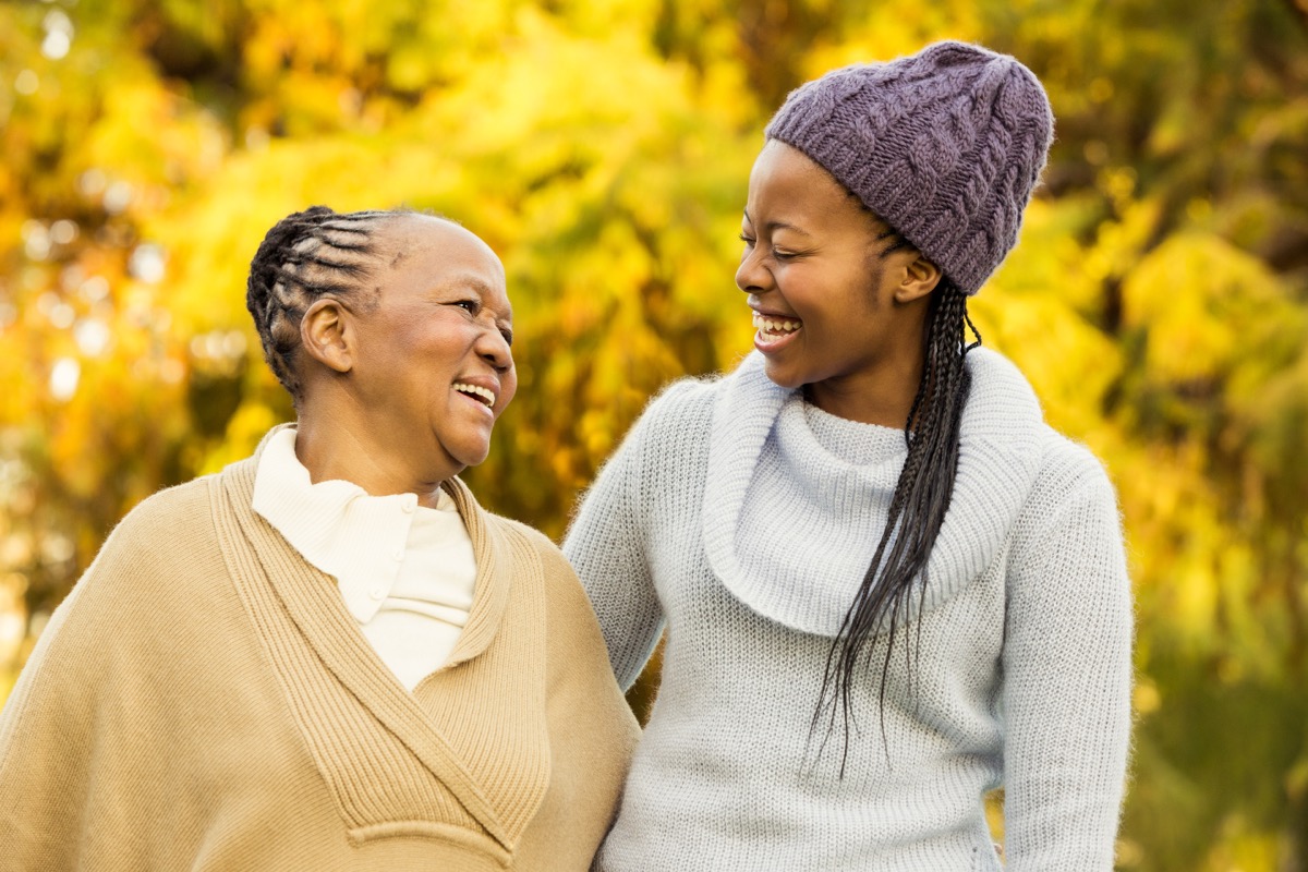 happy older woman and younger woman walking outdoors in fall