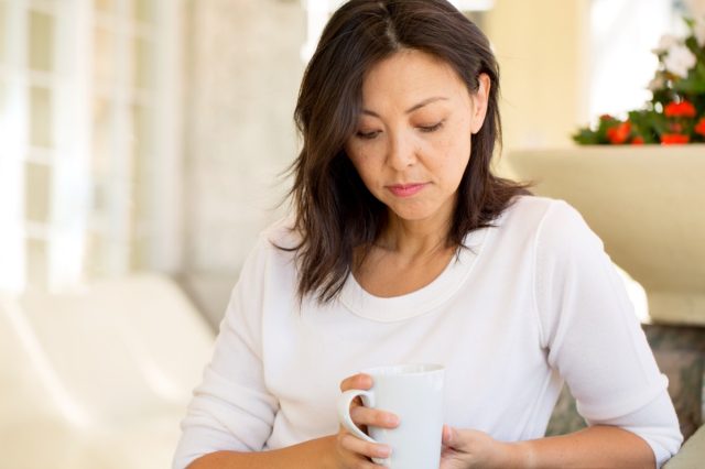Concerned woman looking worried on a sofa.
