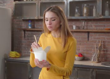 woman standing and eating chinese food