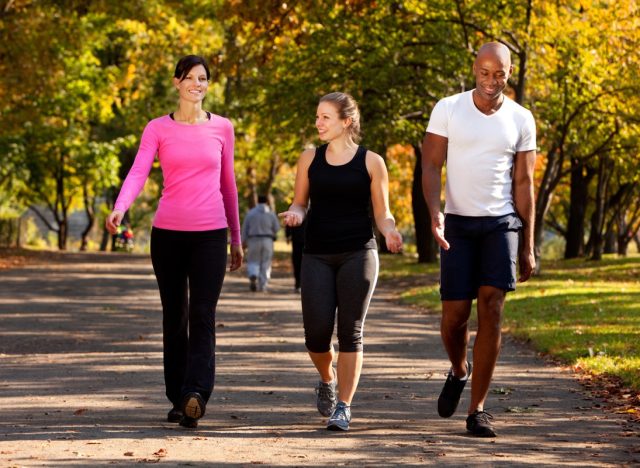 two women and a man walking together in a park