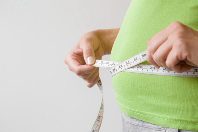 Fat overweight woman measuring her waist