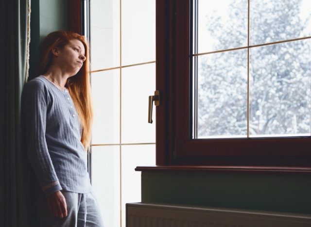 sad woman with winter depression looking out window