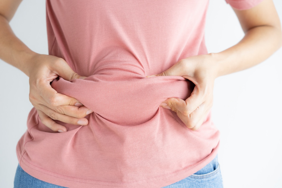Woman hand holding her own belly fat.
