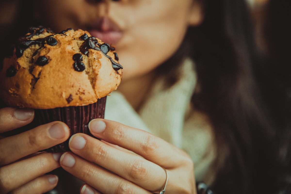 young woman eating chocolate chip muffin