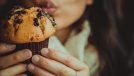 young woman eating chocolate chip muffin