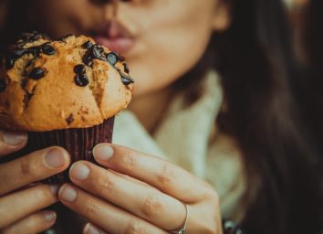 young woman eating chocolate chip muffin