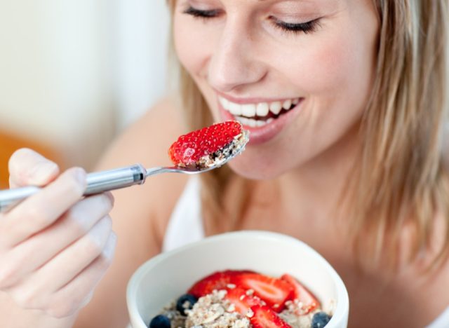 young blonde woman eating berries and oatmeal