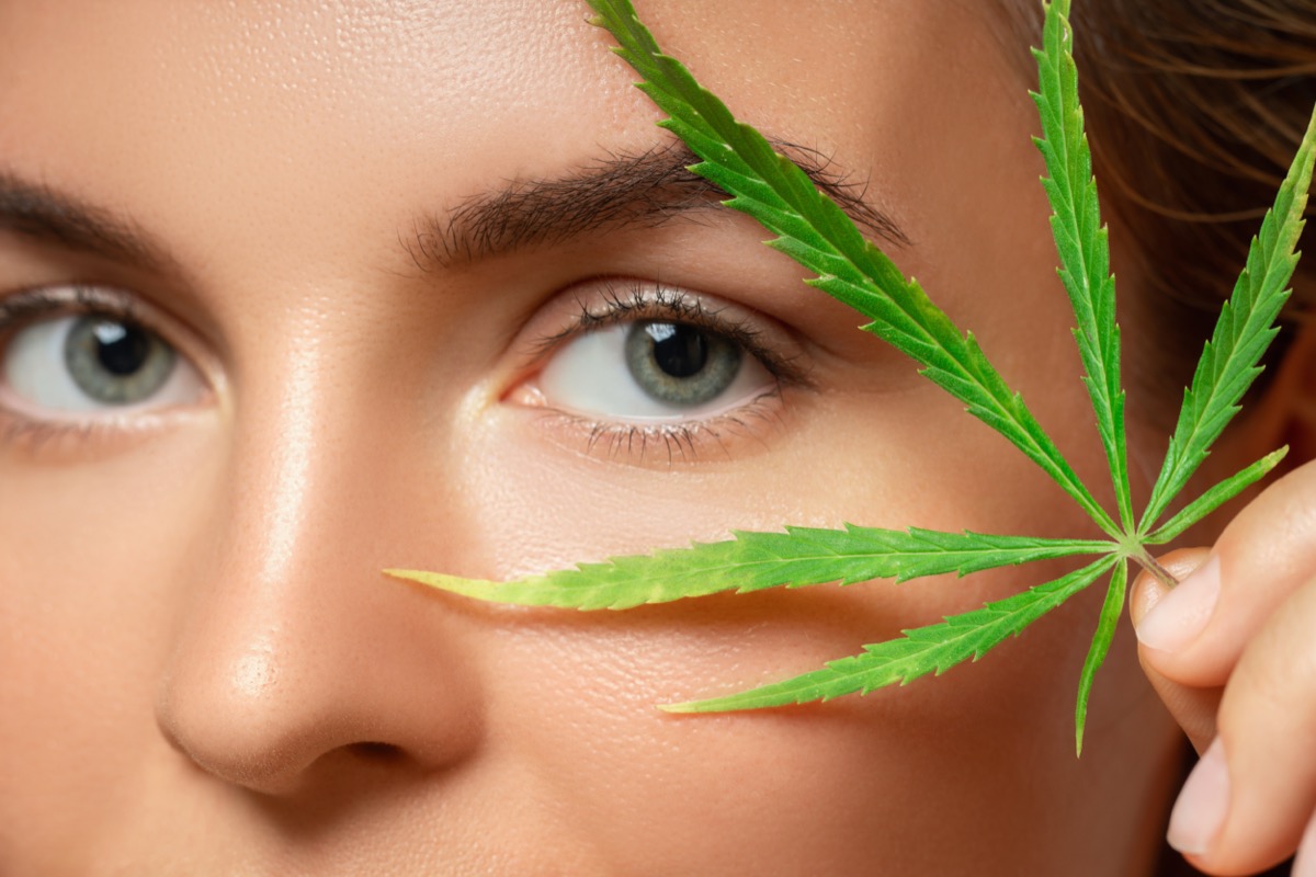 Woman with a cannabis leaf on gray background.