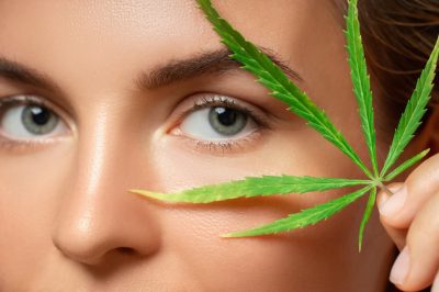 Woman with a cannabis leaf on gray background.