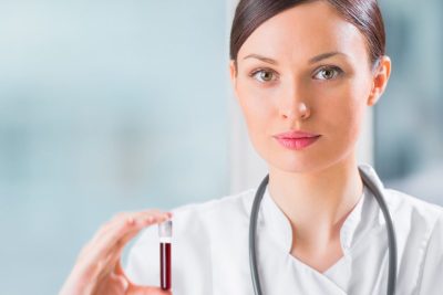 Female laboratory assistant analyzing a blood sample at hospital.