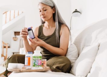 middle-aged woman looking at supplement bottles