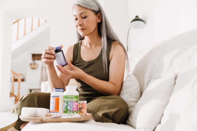 middle-aged woman looking at supplement bottles