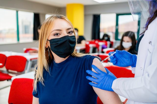 A nurse gives students vaccinations at school during a coronavirus pandemic