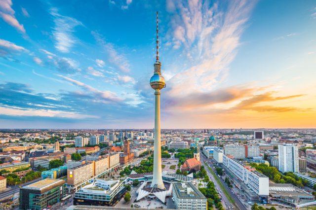 Aerial view of Berlin skyline with famous TV tower at Alexanderplatz and dramatic cloudscape at sunset.