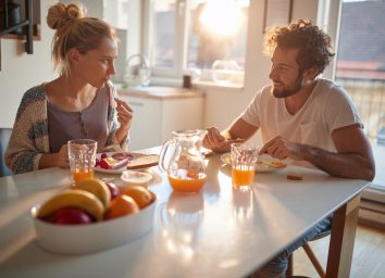 young couple eating breakfast at kitchen table
