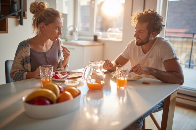 young couple eating breakfast at kitchen table